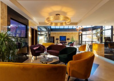 Stilvolle Lobby des Residenz Seehotel mit modernen, farbenfrohen Sesseln und eleganten Leuchten, die eine einladende und entspannte Atmosphäre für Gäste schaffen, ideal für Gespräche oder zum Genießen eines Drinks.