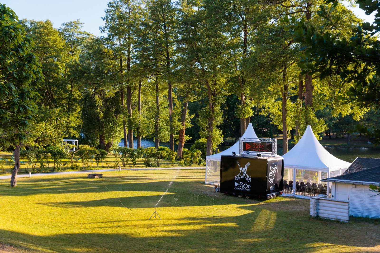 Bereitgestellte Outdoor-Hochzeitslocation im Residenz Seehotel mit eleganter Bühne und Zelten, umgeben von einem ruhigen Park am See, ideal für traumhafte Hochzeitsfeiern im Grünen.