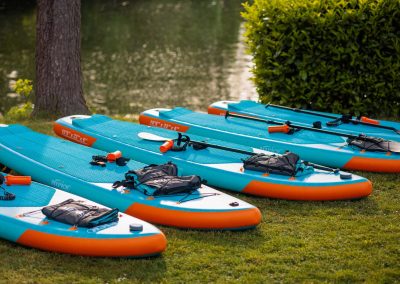 Bunte Stand-Up Paddle Boards am Ufer eines ruhigen Sees, bereit für eine aktive Freizeitgestaltung, ideal für Gäste des Residenz Seehotel, die Natur und Wassersport genießen möchten.